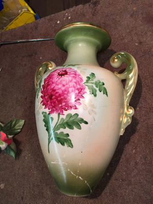 Porcelain vase with green and pink floral design, displaying cracks prior to restoration work.